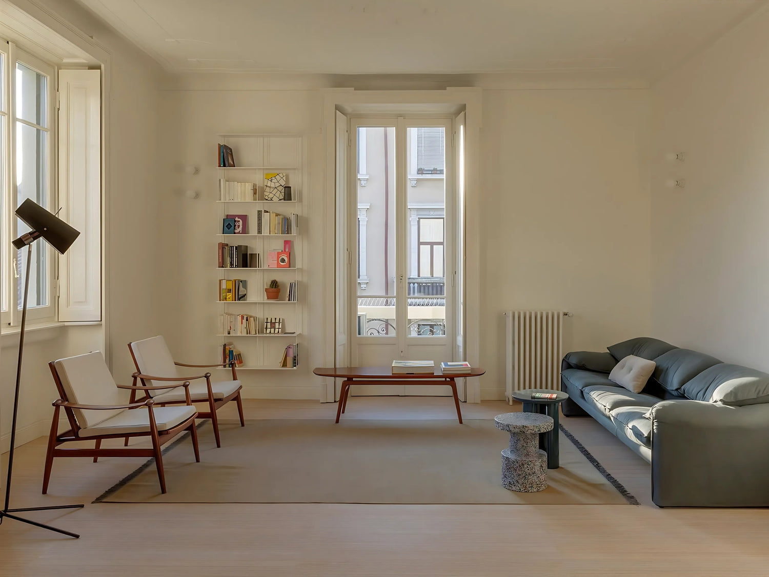 White Krossing bookshelf by Kriptonite in wodern living room with a sofa, chairs, and a coffee table.